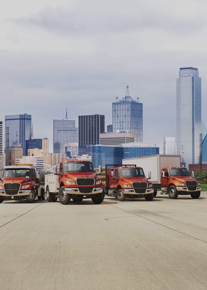 A group of trucks parked in front of a city