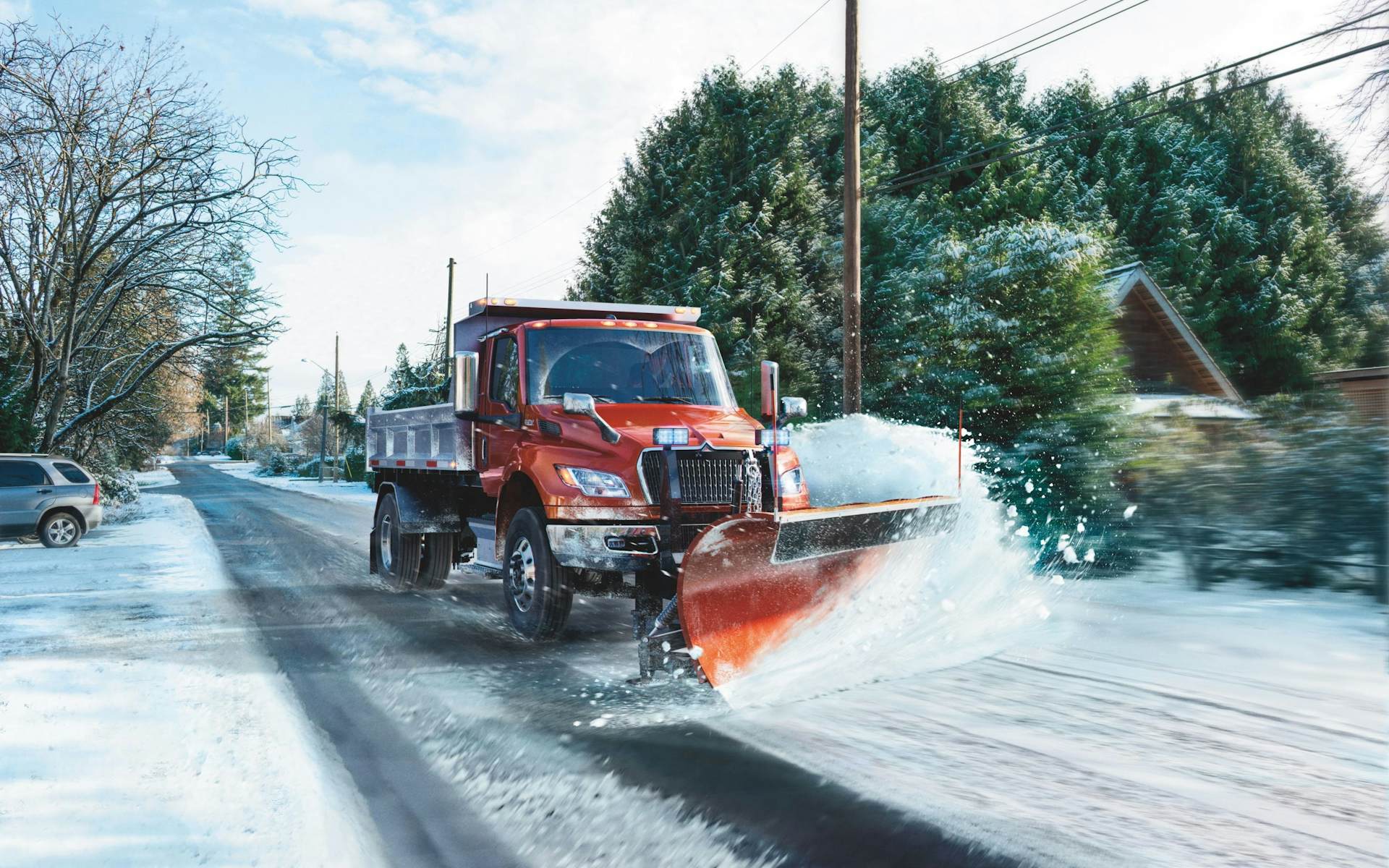 A truck with a snow plow driving along a snowy road