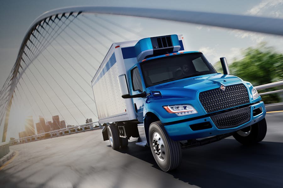Blue truck driving on road under bridge