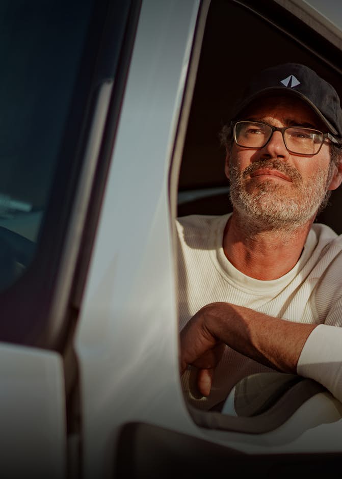 A man with an International hat driving a truck