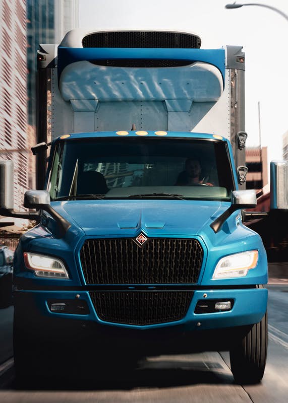 A blue truck driving on the road