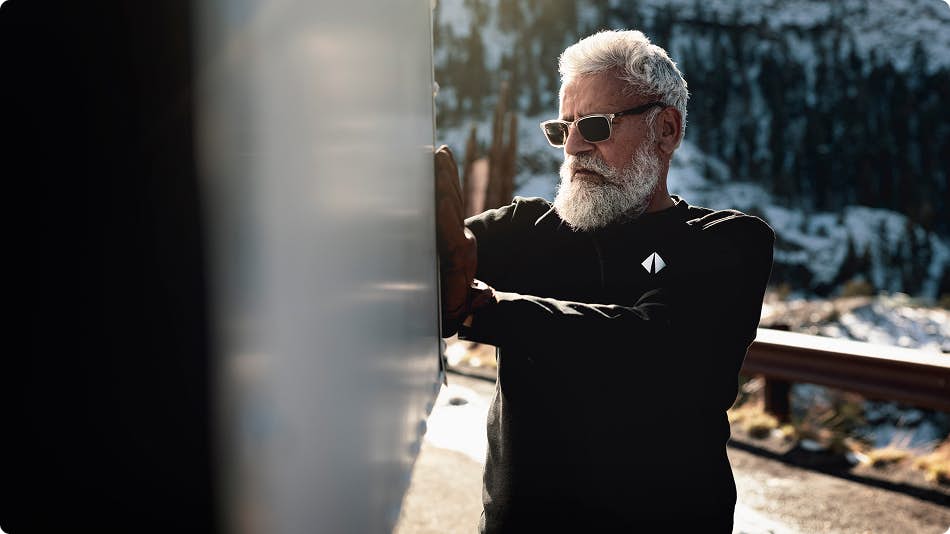 Man with beard and sunglasses with black shirt behind truck